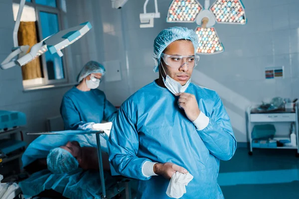 Selektive Fokussierung des Arztes in Uniform, der die medizinische Maske im Operationssaal ablegt — Stockfoto