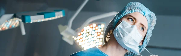 Tiro panorâmico de enfermeira adiando máscara médica na sala de cirurgia — Fotografia de Stock