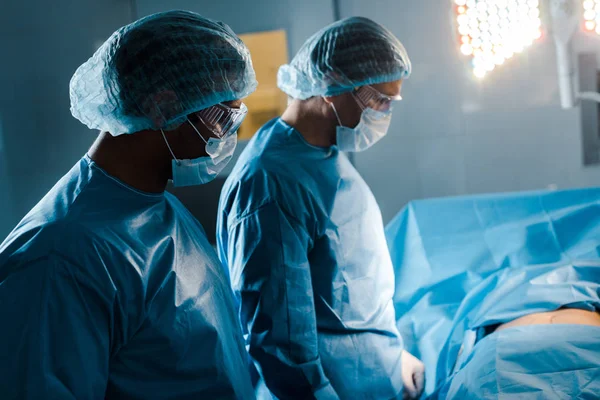 Infermiere e medico in uniforme e maschere mediche in sala operatoria — Foto stock