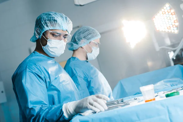 Медсестра та хірург в уніформі та медичній масці, що тримає медичне обладнання — стокове фото