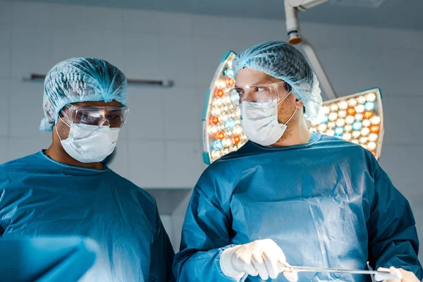 Nurse and surgeon in uniforms and medical masks doing operation — Stock Photo