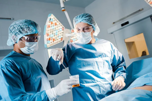 Infermiere e chirurgo in uniforme e maschere mediche che operano in sala operatoria — Foto stock