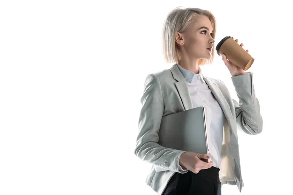 Bela empresária segurando laptop e beber café de copo de papel isolado no branco — Fotografia de Stock