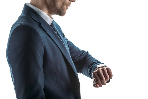 Частковий вигляд серйозного бізнесмена, який дивиться на годинник ізольовано на білому — стокове фото