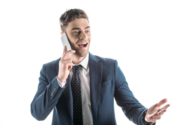 Homem de negócios bonito e alegre usando smartphone e gesticulando isolado no branco — Fotografia de Stock