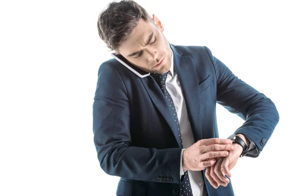 Gutaussehender, seriöser Geschäftsmann, der am Smartphone spricht und vereinzelt auf weiße Armbanduhren blickt — Stockfoto