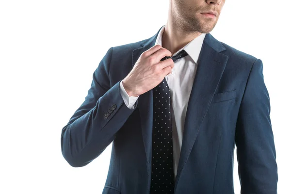 Partial view of businessman in suite touching tie isolated on white — Stock Photo