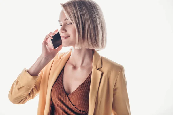 Sonriente, hermosa mujer con el pelo rubio hablando en el teléfono inteligente en gris - foto de stock