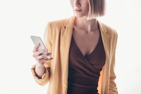 Vista parcial de la mujer de moda sosteniendo teléfono inteligente en gris - foto de stock