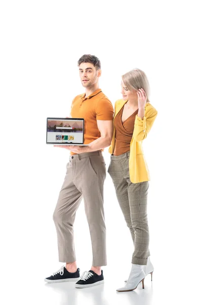 Good-looking man holding laptop with shutterstock website on screen while standing near attractive woman isolated on white — Stock Photo