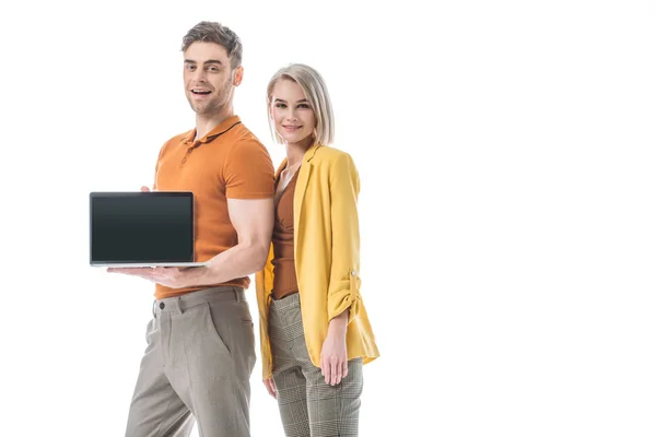 Bel homme souriant tenant ordinateur portable avec écran blanc tout en se tenant près de femme assez surprise isolé sur blanc — Photo de stock