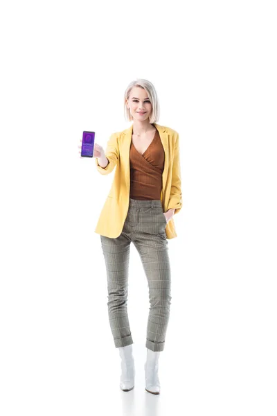 Atractiva mujer rubia sosteniendo teléfono inteligente con aplicación de compras en línea en la pantalla aislada en blanco - foto de stock