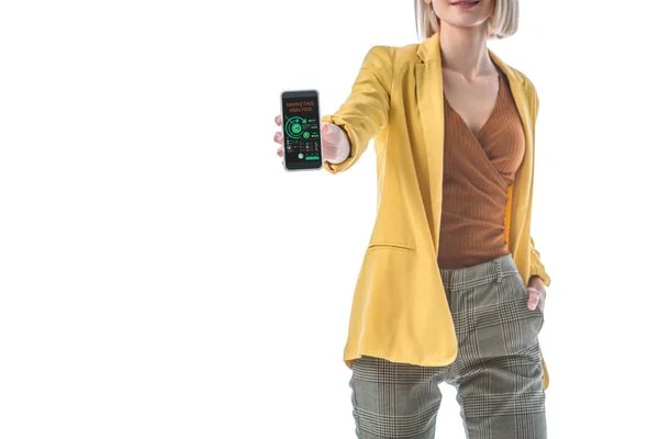 Visão parcial da mulher com mão no bolso segurando smartphone com aplicativo de análise de marketing na tela isolada no branco — Fotografia de Stock
