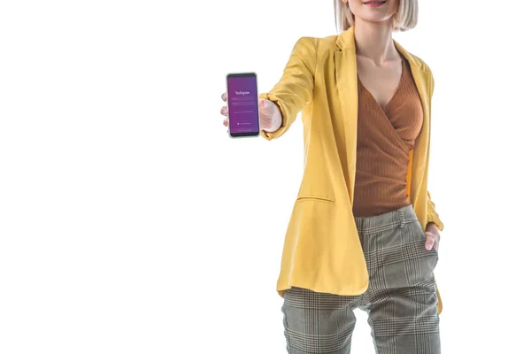 Частичный вид модной женщины, держащей смартфон с приложением Instagram на экране, изолированном на белом — стоковое фото