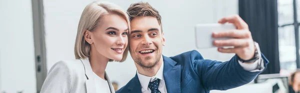Plano panorámico de socios de negocios alegres tomando selfie en la oficina juntos - foto de stock
