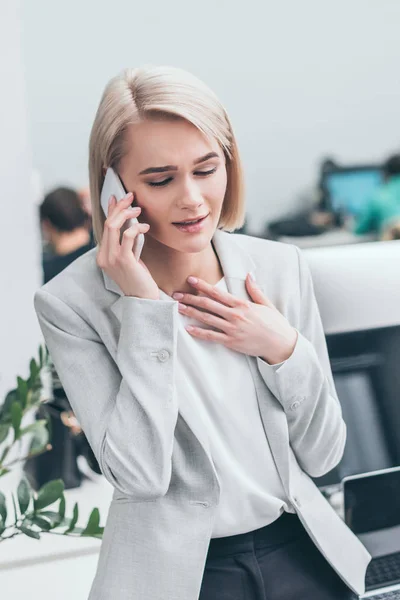 Schöne, traurige Geschäftsfrau, die im Büro auf dem Smartphone spricht — Stockfoto