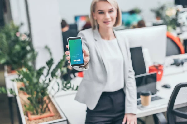 Attraktive Geschäftsfrau mit Smartphone und Twitter-App auf dem Bildschirm im Fokus — Stockfoto