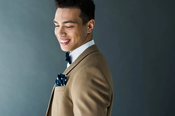 Stylisches Mixed Race Mann in Anzug und Fliege lächelnd isoliert auf grau mit Kopierraum — Stockfoto