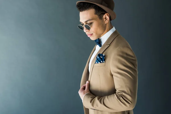 Stylischer Mixed Race Mann in Anzug und Sonnenbrille posiert isoliert auf grau mit Kopierraum — Stockfoto