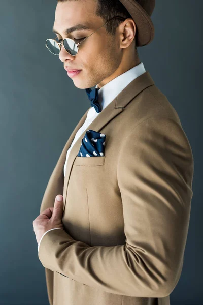 Hombre de raza mixta de moda en traje y gafas de sol posando aislados en gris - foto de stock