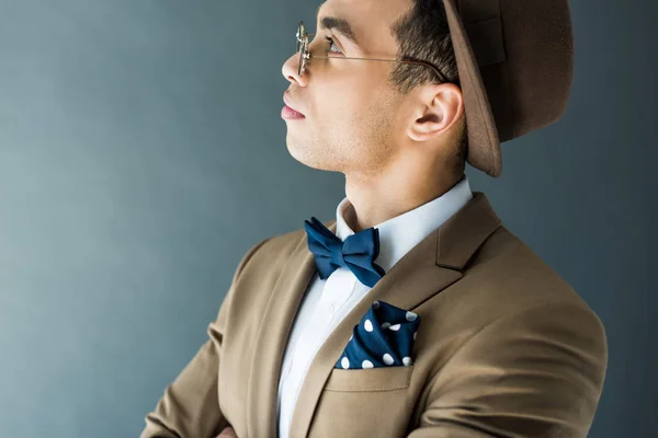 Side view of stylish mixed race man in suit and sunglasses posing isolated on grey with copy space — Stock Photo