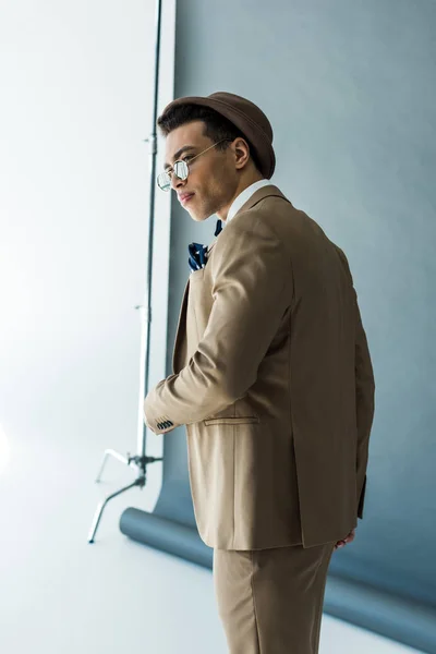 Uomo di razza mista alla moda in abito e cappello in posa su grigio — Foto stock