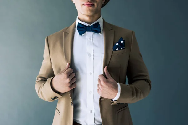 Partial view of stylish mixed race man in suit and bow tie posing isolated on grey — Stock Photo