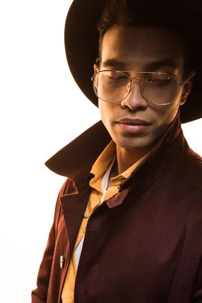 Elegante hombre de raza mixta en gafas de sol y sombrero posando aislado en blanco - foto de stock