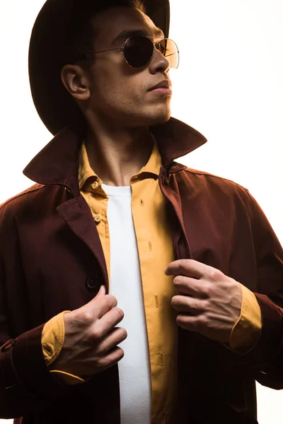 Stylish mixed race man in sunglasses and hat looking away while posing isolated on white — Stock Photo