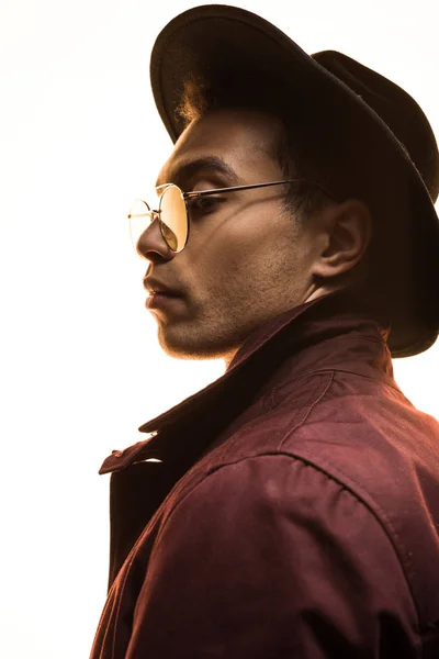 Vue latérale de l'homme mixte élégant dans le chapeau et les lunettes de soleil posant isolé sur blanc — Photo de stock