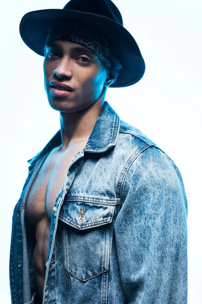 Handsome stylish mixed race man in denim and hat looking at camera isolated on white — Stock Photo