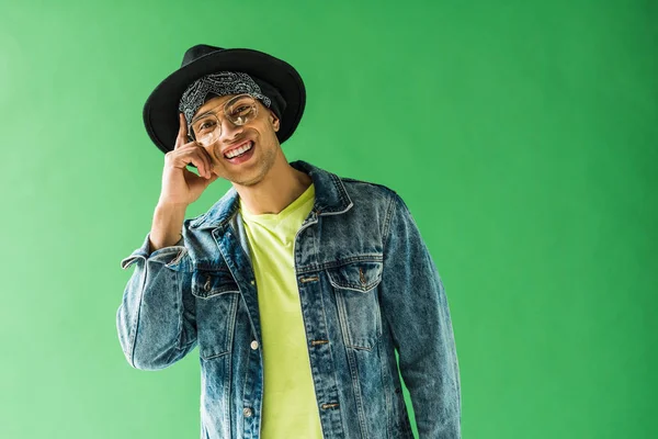 Stylish mixed race man looking at camera, smiling and showing idea gesture on green screen — Stock Photo