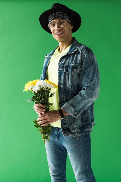 Stilvoller Mischlingsmann mit Blumen, der in die Kamera schaut und auf dem grünen Bildschirm lächelt — Stockfoto