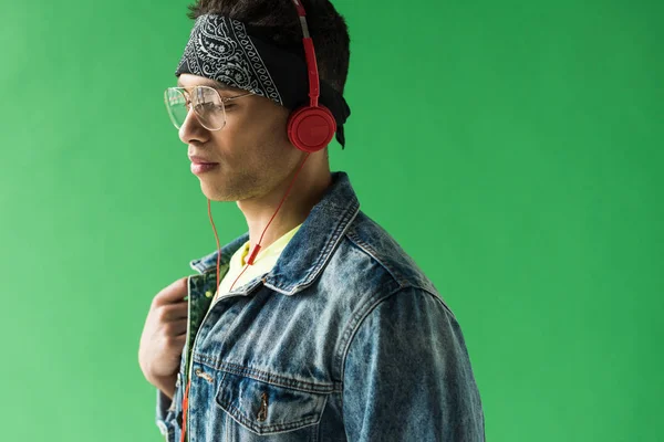 Handsome mixed race man in headphones listening music on green screen with copy space — Stock Photo