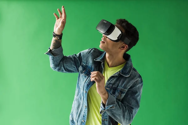 Mixed race man in vr headset gesturing while experiencing virtual reality on green screen — Stock Photo