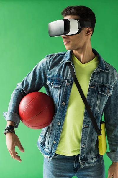 Uomo razza mista in cuffia realtà virtuale tenendo pallacanestro sullo schermo verde — Foto stock