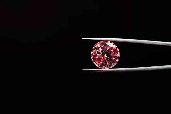 Colorful red sparkling diamond in tweezers isolated on black — Stock Photo