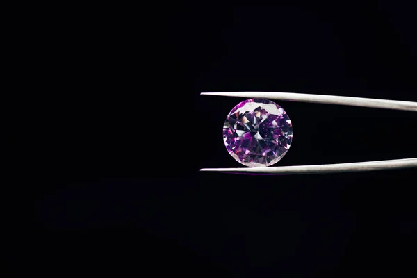 Colorful purple sparkling diamond in tweezers isolated on black — Stock Photo