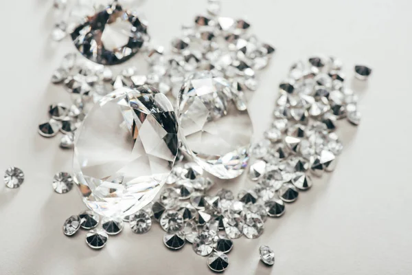 Selective focus of transparent pure big diamonds among small on white background — Stock Photo