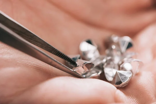 Close up of tweezers near shiny diamonds in hand — Stock Photo