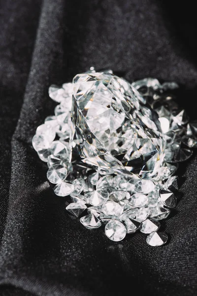 Pile of sparkling pure diamonds on black shiny cloth — Stock Photo