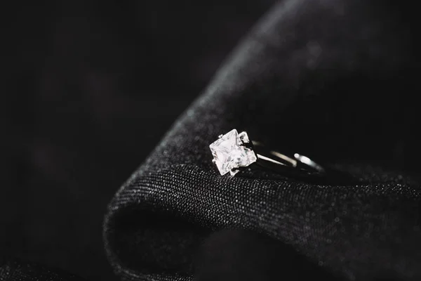 Bague de fiançailles avec diamant brillant pur sur tissu noir — Photo de stock