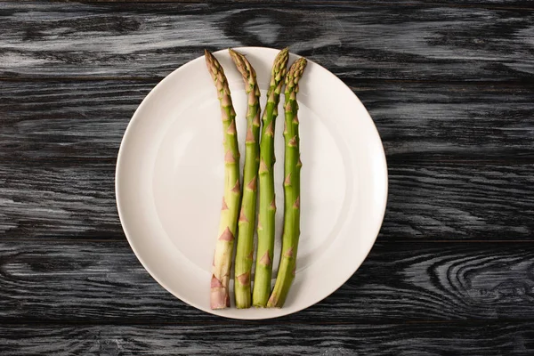 Vista dall'alto di asparagi biologici su piatto su fondo grigio in legno — Foto stock