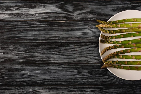 Vista dall'alto di asparagi biologici verdi su piatto su fondo grigio in legno con spazio copia — Foto stock