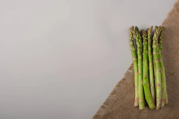 Ansicht von grünem Spargel auf Sacktuch auf grauem Hintergrund — Stockfoto