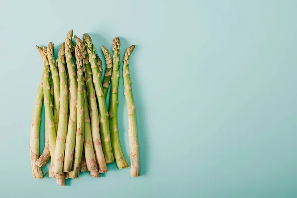 Draufsicht auf grünen rohen Spargel auf blauem Hintergrund mit Kopierraum — Stockfoto