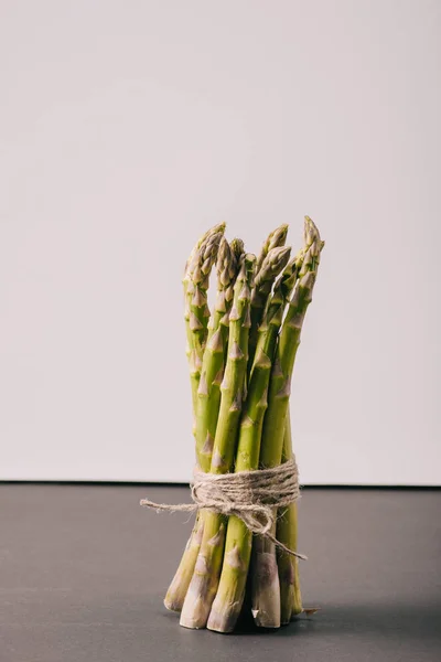 Mazzo di asparagi verdi legati con corda su superficie grigia — Foto stock