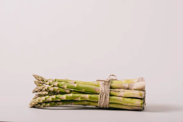 Mazzo di asparagi verdi legati con corda su fondo grigio — Foto stock