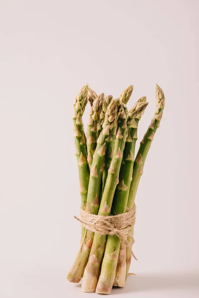 Mazzo di asparagi grezzi verdi legati con corda su fondo grigio — Foto stock