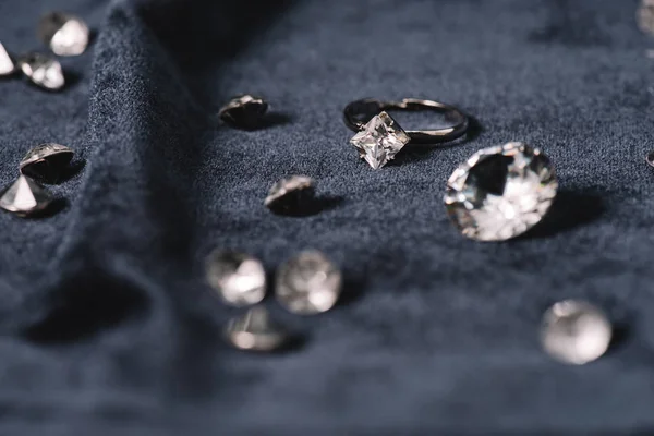 Selective focus of engagement ring near shiny diamonds on blue cloth — Stock Photo